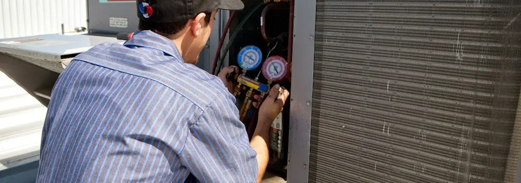 HVAC technician servicing a condenser unit in Hartland